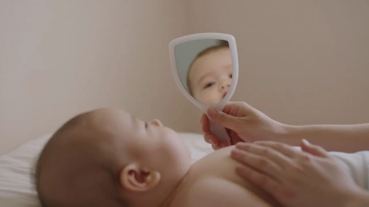 Miminko se dívá do malého plastového zrcátka a vidí svou tvář.